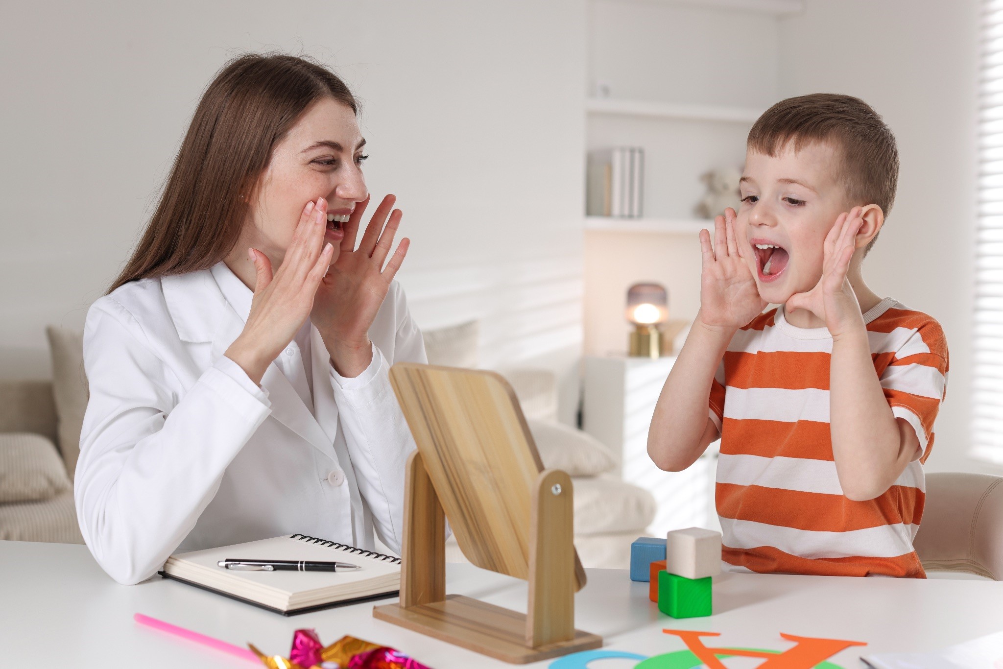 Woman and boy playing a speech therapy game together.