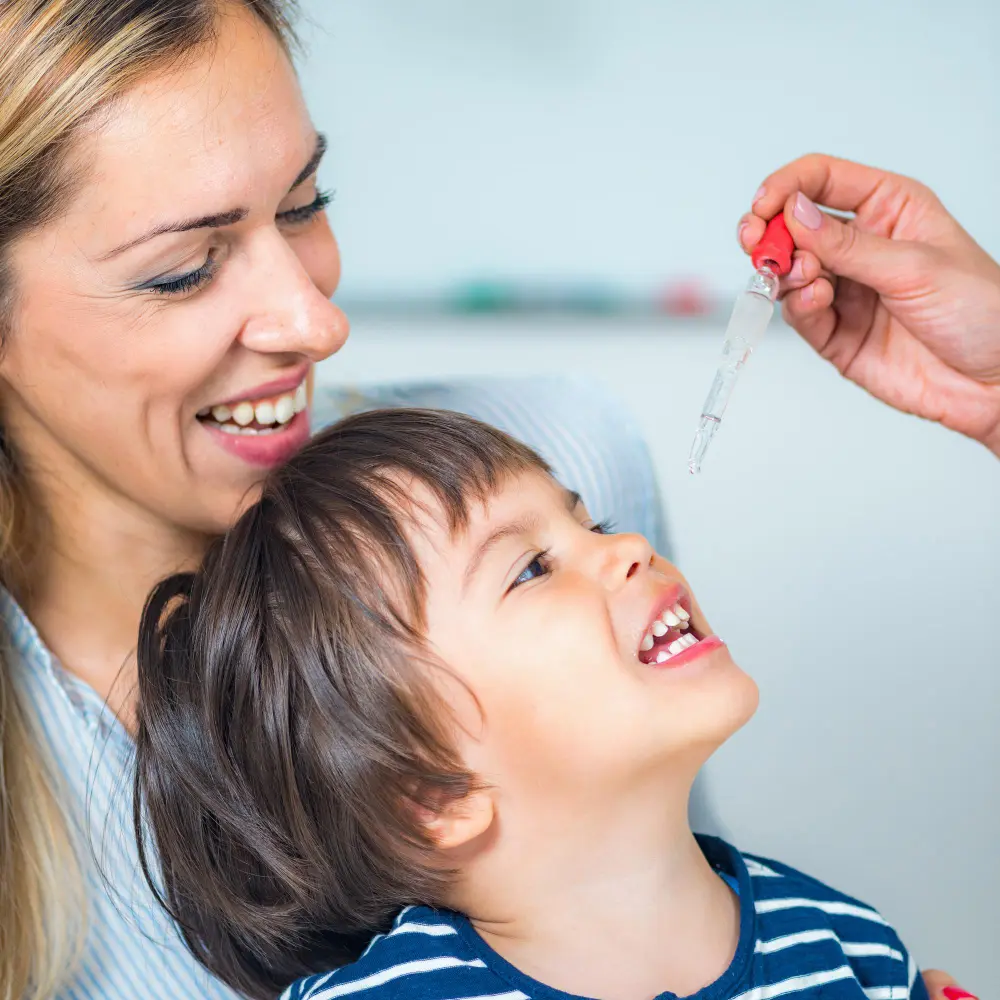Mother feeding her happy child a spoonful of medicine.