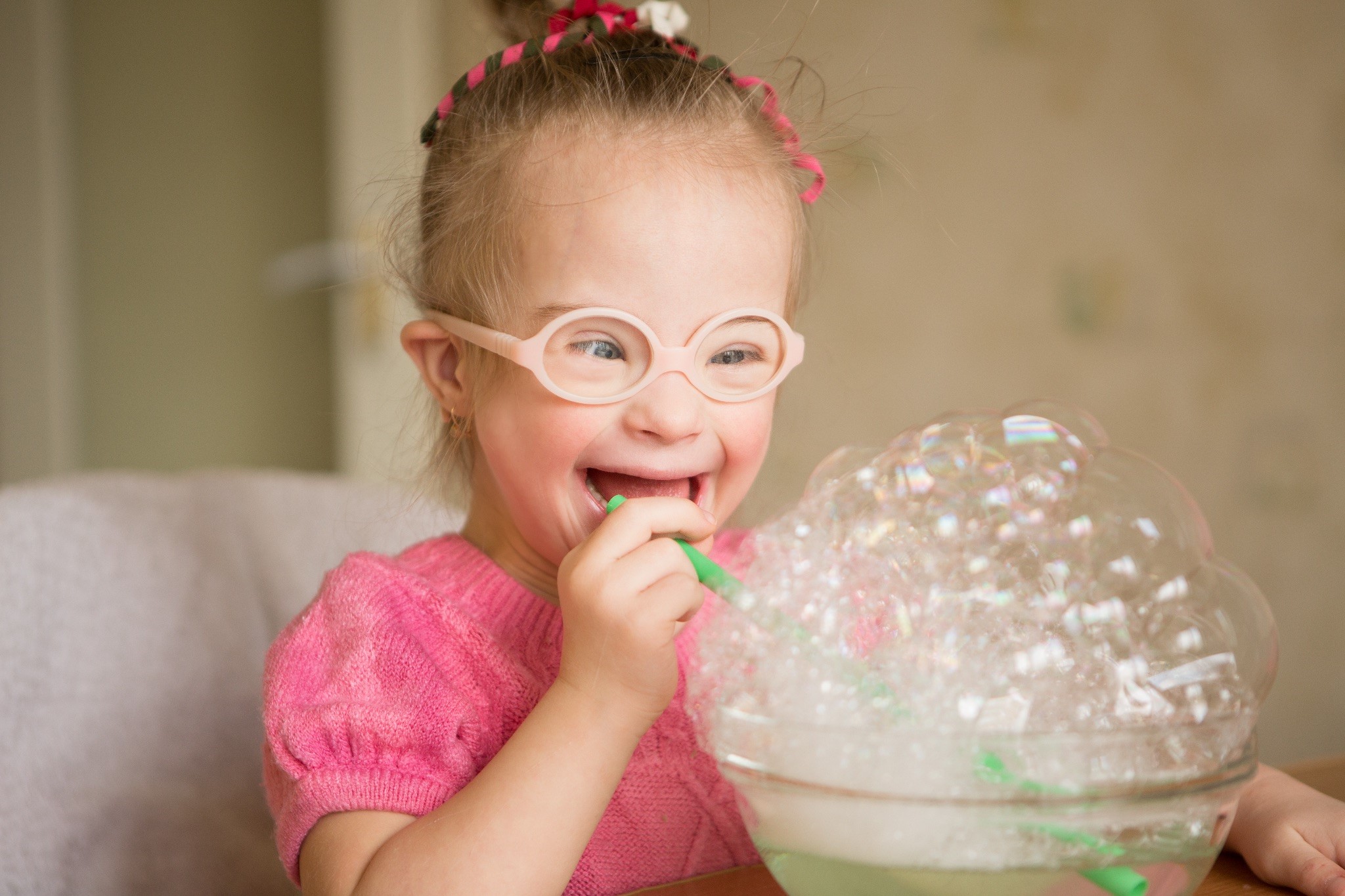 Smiling girl with glasses playing with bubbles.