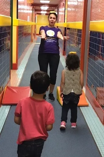 Children walking towards a woman in hallway.